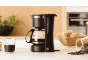 Uma cafeteira elétrica moderna em aço inox passando café fresco em uma cozinha aconchegante, ilustrando a busca pela melhor cafeteira elétrica de 2026.